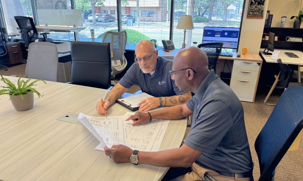 Two men consulting about an office furniture project at Office Furniture EZ's showroom