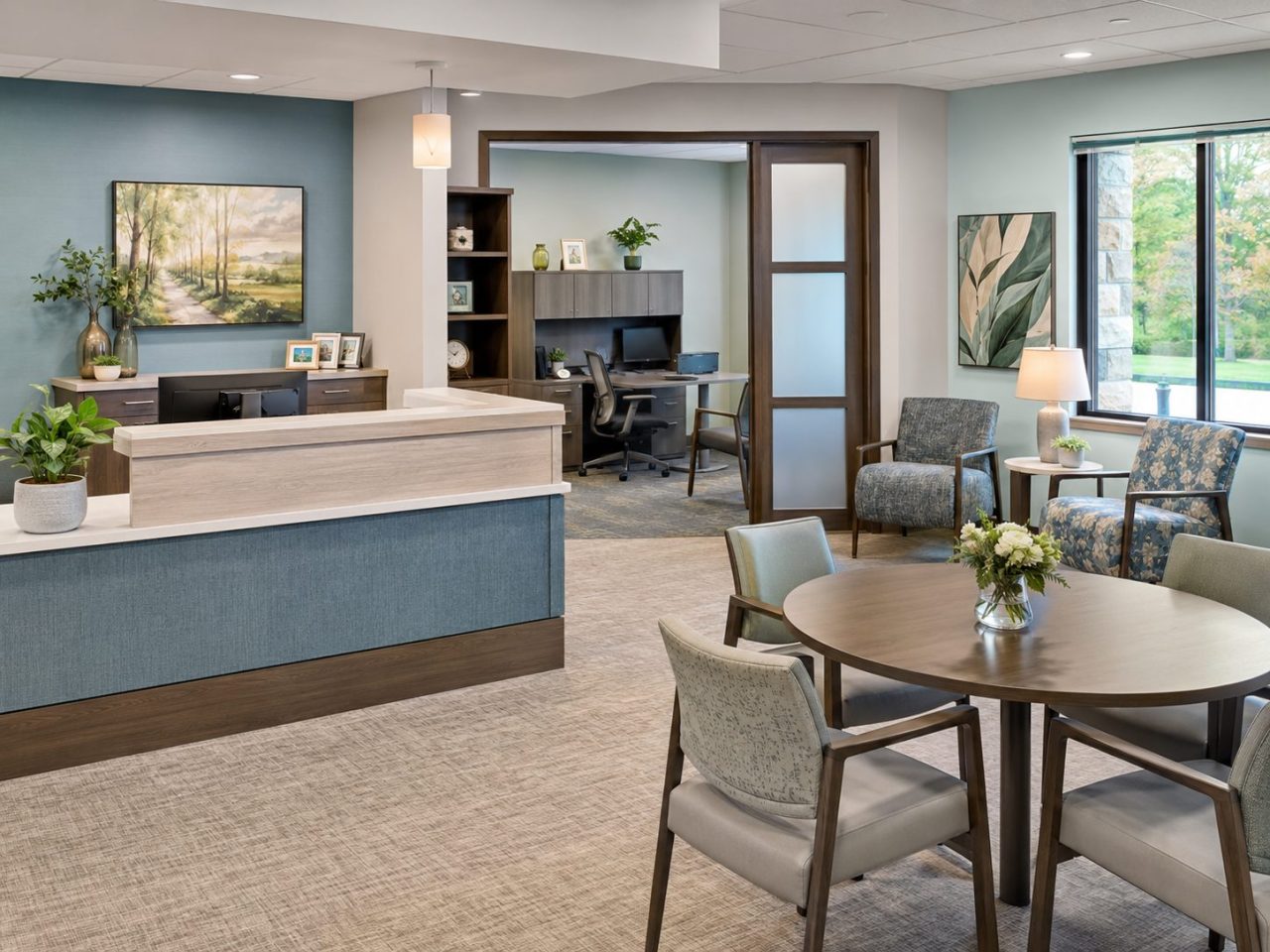 Senior care reception area with front desk, consultation workspace, lounge seating, and round meeting table