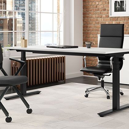 A white standing desk shown in a professional office with a chair and other accessories