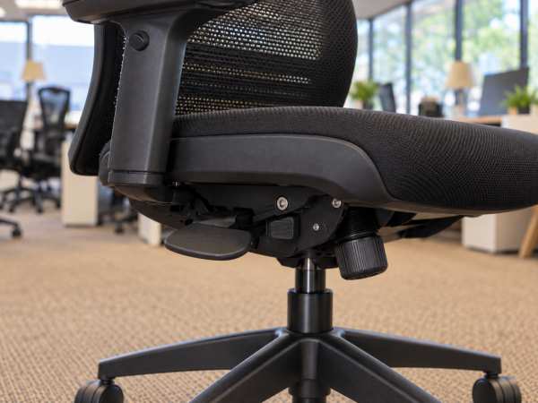Close-up of the levers and tilt-tension dial on an adjustable ergonomic office chair.