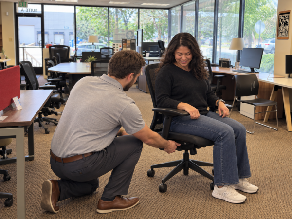 A customer receives help adjusting an ergonomic office chair in the Office Furniture EZ Denver showroom.